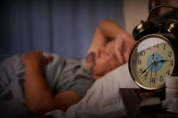 istock depressed old man and stressed lying in bed from insomnia,focus on the clock 1415713883