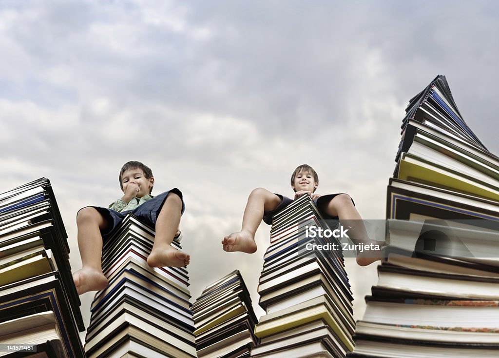 Children sitting on books tower Successful little kids on top of books, conceptual image Book Stock Photo