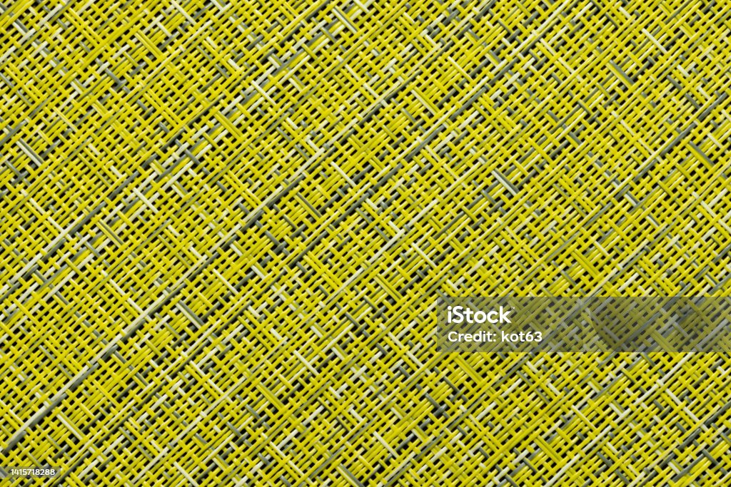 Backgrounds and textures made of synthetic materials. A fragment of a straw rug, as a background or texture, yellow and gray color, close-up. Pattern Stock Photo