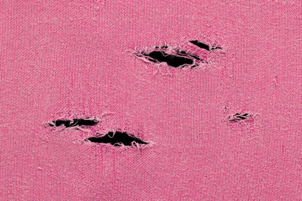 A fragment of a pink fabric with holes, as a background or texture, close-up.