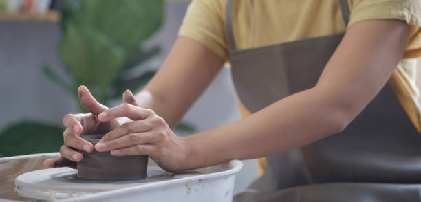 istock Young craftswoman working on pottery wheel in handmade ceramics workshop. Creative activities, pottery, ceramics art concept. 1415725456