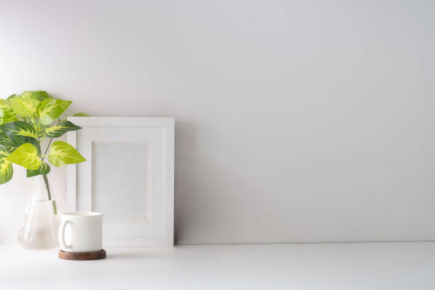 istock Minimal workplace with flower pot and picture frame on white table. Home office, Copy space for text. 1415725815