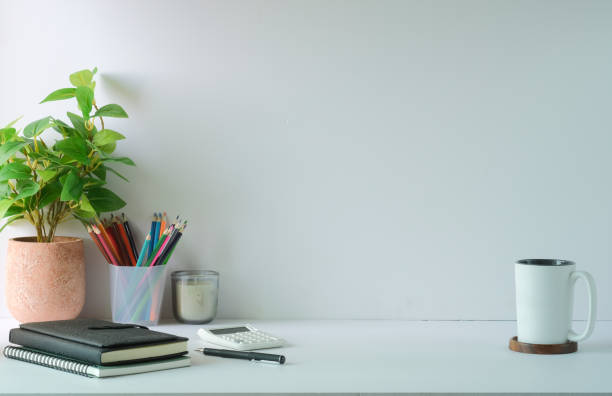 istock Creative workplace with potted plant, stationery, calculator and colourful sticky notes on light wall. 1415725820