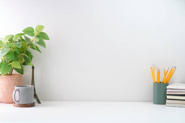 istock Minimal workplace with picture frame, potted plant and coffee cup on white table. Copy space for advertise text, information content. 1415725832