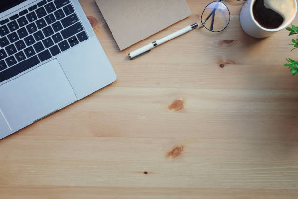 istock Computer laptop, eyeglasses, coffee cup and notebook on wooden desk. Top view. 1415725848
