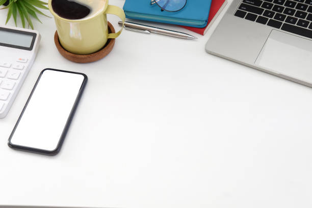 istock Mockup smart phone, calculator, coffee cup and wireless earphone on white office desk. 1415725857