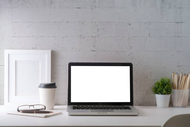 istock Home office desk with laptop computer, picture frame, coffee cup, and pencil holder on white table against brick wall. 1415726540