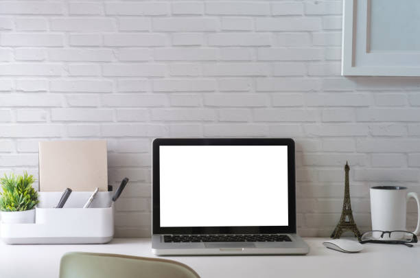 istock Mock up laptop computer, picture frame, coffee cup, books and pencil holder on white office desk. 1415726557