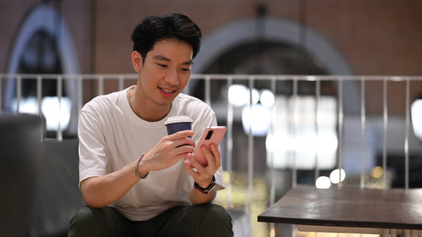 istock Handsome asian man chatting online or checking social media on mobile phone while in modern cafe. 1415727410