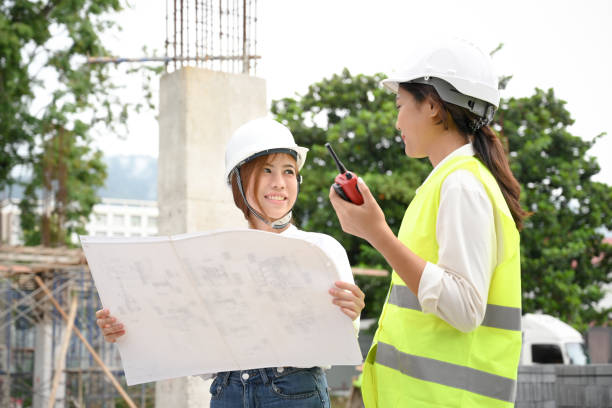 建設現場で女性土木技師と話す優秀なアジア人女性建築家。 - construction worker manual worker construction group of people ストックフォトと画像