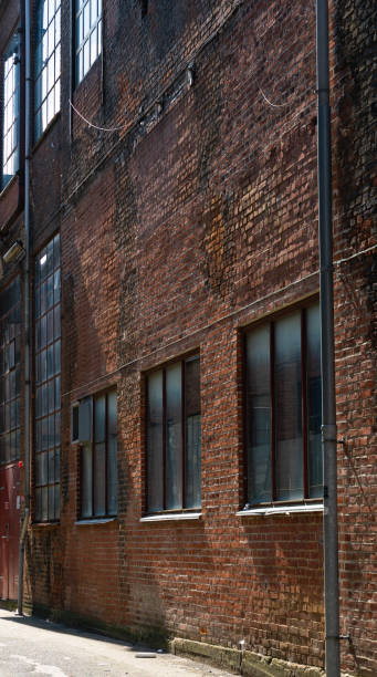 istock Old rugged factory facade with bricks and large windows inside a large city. 1415730457