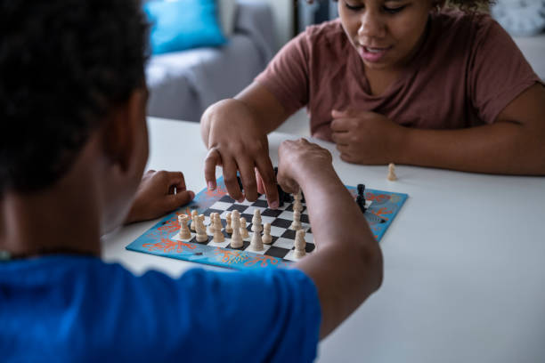 istock Hands in action. Two black kids play chess at home. 1415730497
