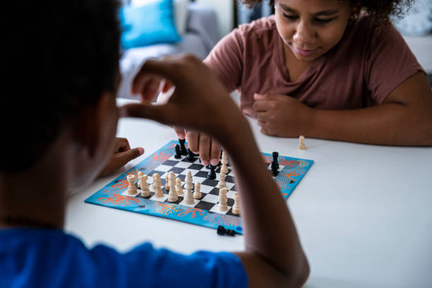 istock Hands in action. Two black kids play chess at home. 1415730498