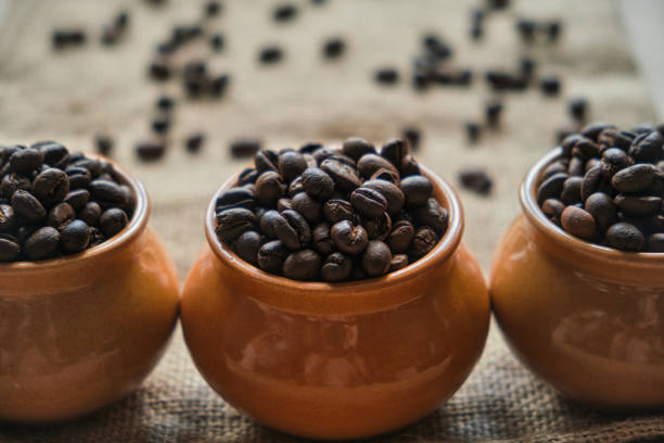 Clay pots filled with fresh roasted coffee beans, close-up. Assortment of coffee varieties for connoisseurs of refreshing drink.