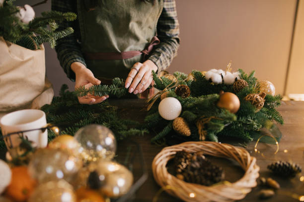 istock Millennial woman making Christmas wreath using pine branches and festive decorations in workshop. Small business 1415734775