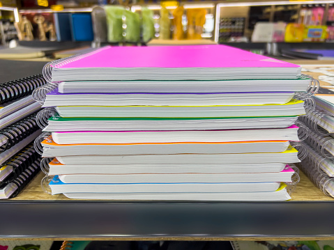 Back to School Educational concept: Closeup on colorful spiral ring books in a stationary store. Selection of multi-colored cardboard covered notebooks stacked. Shopping for school and office supplies. Side view. No brands.