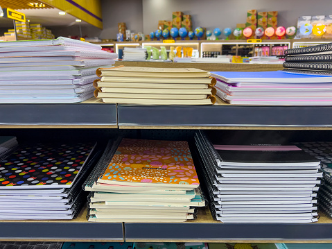 Back to School Educational concept: Closeup on colorful spiral ring books in a stationary store. Selection of multi-colored cardboard covered notebooks stacked. Shopping for school and office supplies. Side view. No brands.