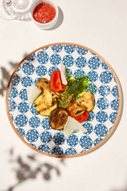 istock Grilled vegetables on light background with shadows. Grilled zucchini, eggplant, paprika, mushrooms. Aesthetic composition with bbq vegetables. Vegan food. Grilled vegetables in Summer menu. 1415737447