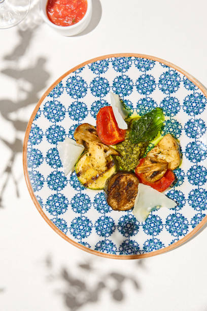 istock Grilled vegetables on light background with shadows. Grilled zucchini, eggplant, paprika, mushrooms. Aesthetic composition with bbq vegetables. Vegan food. Grilled vegetables in Summer menu. 1415737818