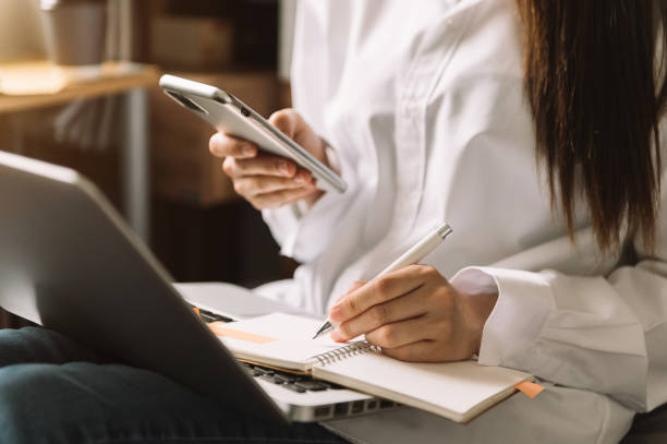 istock Motivated young business planing her strategy while typing on laptop, tablet and writing on notebook 1415738140