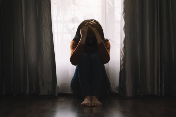 istock woman sit Depression Standing by window and anxiety 1415738196