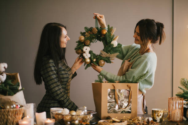 istock Two millennial women making Christmas wreath using fresh pine branches and festive decorations. 1415741792