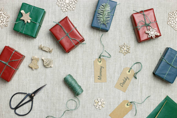 istock Christmas colorful handmade gift boxes on textile background, making green, red paper wrapped xmas presents with jute thread, holiday aesthetic gifts simple craft present, top view table 1415744682