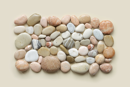 Aesthetic minimal pattern with set of sea pebble stones on beige background. Square composition from natural round smooth stone neutral color. Collection of rocks, summer concept, top view, flat lay