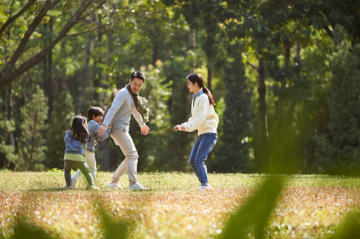 young asian family with two children having fun playing in park