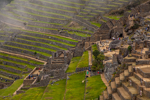 Machu Picchu, Aguas Calientes, Peru - March 19, 2023; Machu Picchu is a 15th-century Inca citadel located in the Eastern Cordillera of southern Peru on a 2,430-meter (7,970 ft) mountain ridge. It is located in the Machupicchu District within Urubamba Province  above the Sacred Valley, which is 80 kilometers (50 mi) northwest of Cusco. The Urubamba River flows past it, cutting through the Cordillera and creating a canyon with a tropical mountain climate.\n\nMost recent archaeologists believe that Machu Picchu was constructed as an estate for the Inca emperor Pachacuti (1438–1472). Often referred to as the \