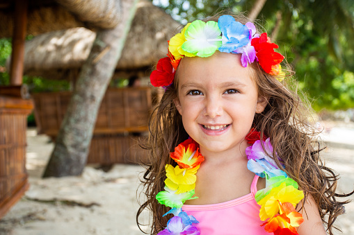 Little girl  dressed with Hawaii lei smiling at the tropical beach