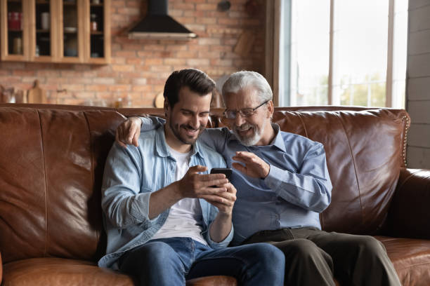 istock Retired male and his grown son making videocall on smartphone 1415754643
