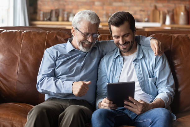 istock Elderly man in glasses use tablet computer with grownup son 1415754647