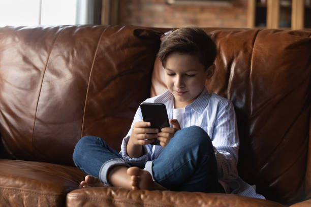 istock Junior school age boy playing online videogame on modern phone 1415754663