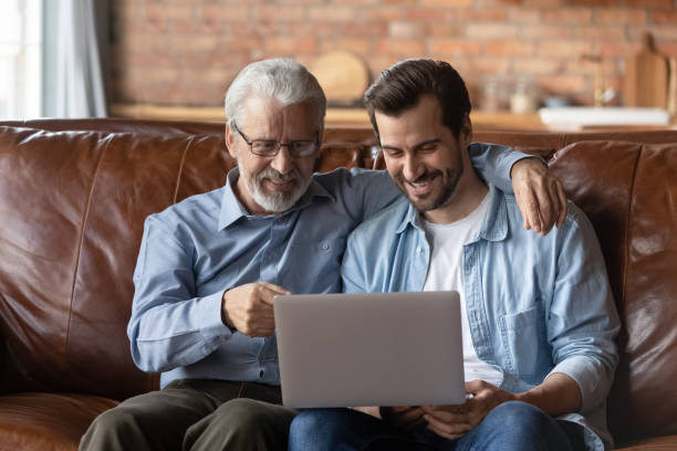 istock Elder and younger men relatives hug look on laptop screen 1415754792