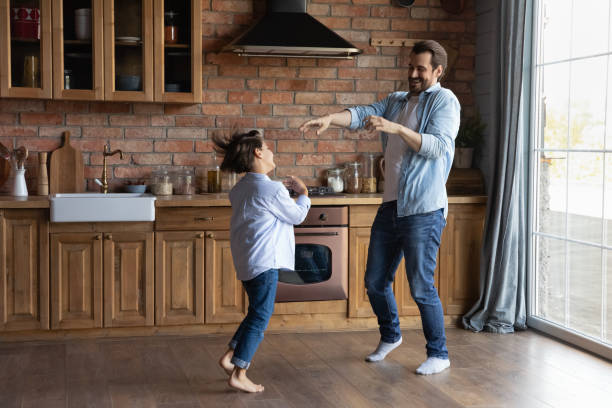 istock Happy young father little son dancing on floor at kitchen 1415754938