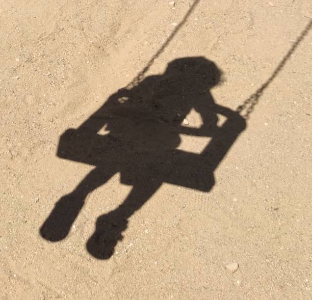istock Shadow of a child on a swing 1415757014