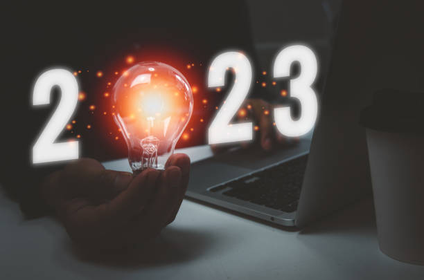istock Business hand holding bulb light text 2023 and computer laptop on desk.Idea innovation growth plan concept. 1415757995