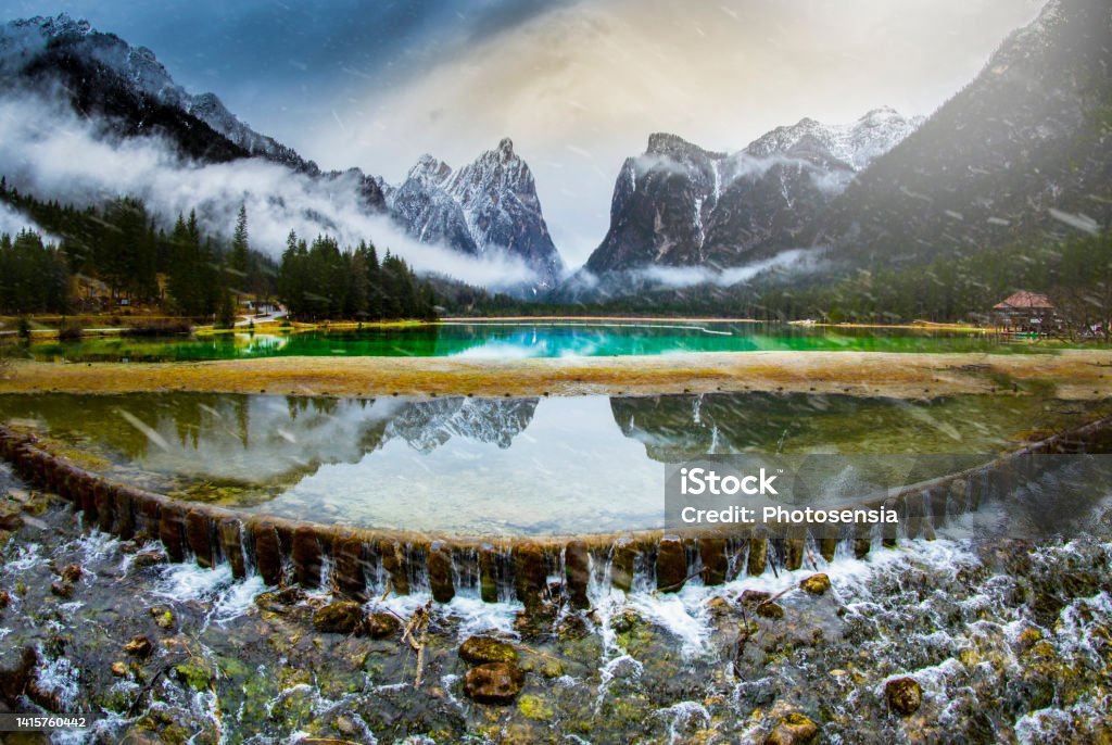 Panoramic over the Toblacher Lake Lago di Dobbiaco and Dolomite mountain summits nearby in Autumn October colors at foggy morning, Dolomites, South Tyrol, Italy Alto Adige - Italy Stock Photo