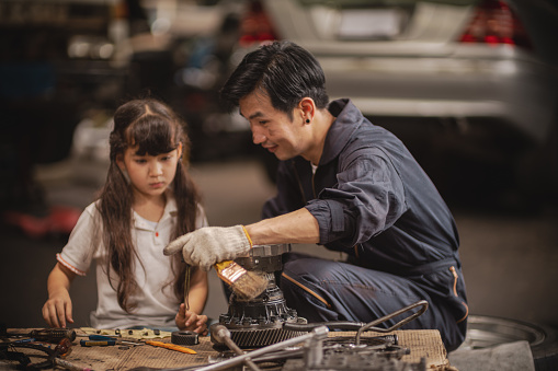 Daughter assisting father in car garage - stock video