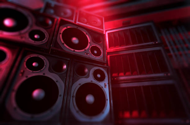 Close up of sound system with large speakers and subwoofers Loudspeakers and subwoofers stacked on each other illuminated by red spotlights on a dark background. Powerful sound system with modern audio equipment for an underground music club where punk and rock music is played. Digitally generated image. Copy space. rock n roll music speakers stock pictures, royalty-free photos & images