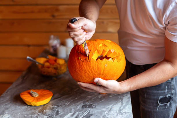 istock Man prepare for Halloween by carving pumpkin. close-up 1415762787