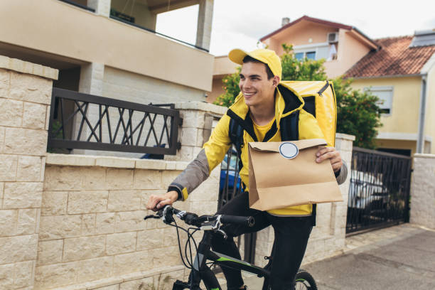 Male courier with bicycle delivering packages Bicycle delivery commuter with road bicycle delivering package to customer part-time delivery job stock pictures, royalty-free photos & images