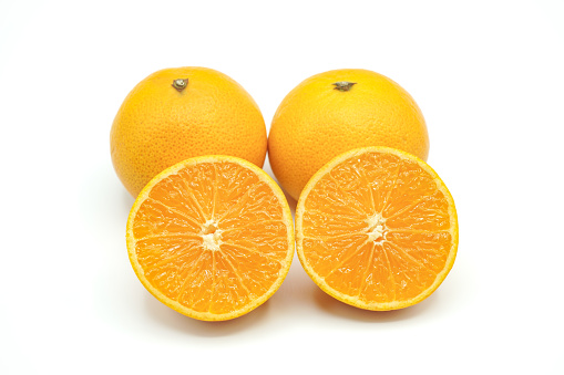 Halved oranges and two oranges look fresh appetizing on white background.