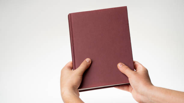 istock Men's hands hold a book or notebook in a burgundy binding on a white background 1415765622