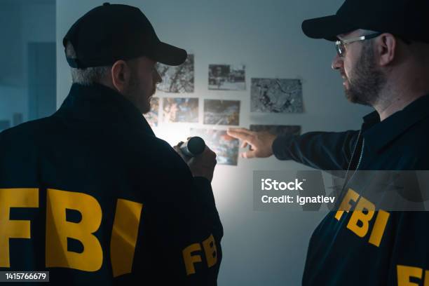 Fbi Agents At Work Exploring Photos On The Wall During Investigation Stock Photo - Download Image Now
