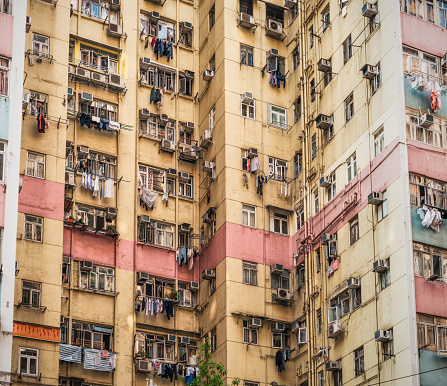 Close-up of a high-rise block of flats in Hong Kong showing signs of ageing, with many residents hanging laundry out of their windows.