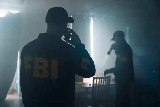 An action movie scene with two FBI agents at the crime scene in a foggy room of the criminal's apartment, calling criminologists on the phone