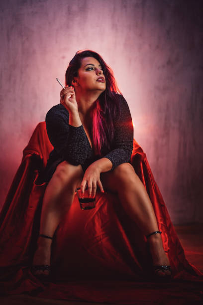 istock Young Plus Size Woman Smoking A Cigarette And Drinking Whiskey While Sitting On A Chair 1415768340