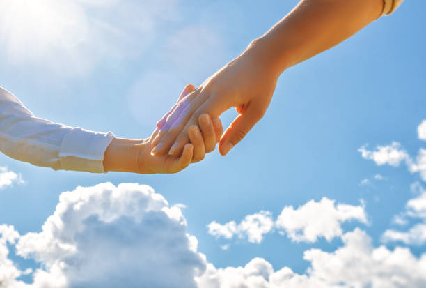 Hands of adult and child on blue sky background stock photo